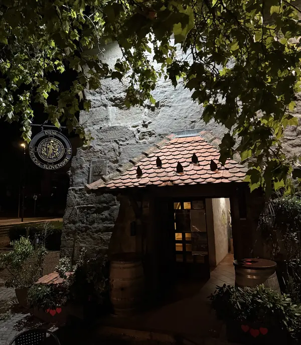 Osvetljen vhod v Vodni stolp ponoči, s sodi in cehovsko tablo