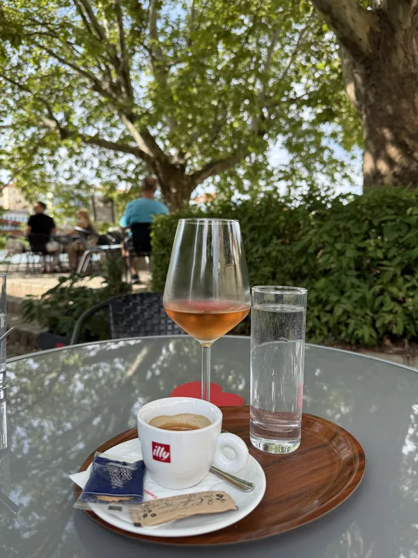 Kozarec rosé vina in kava na mizi na senčni terasi Vinoteke Maribor